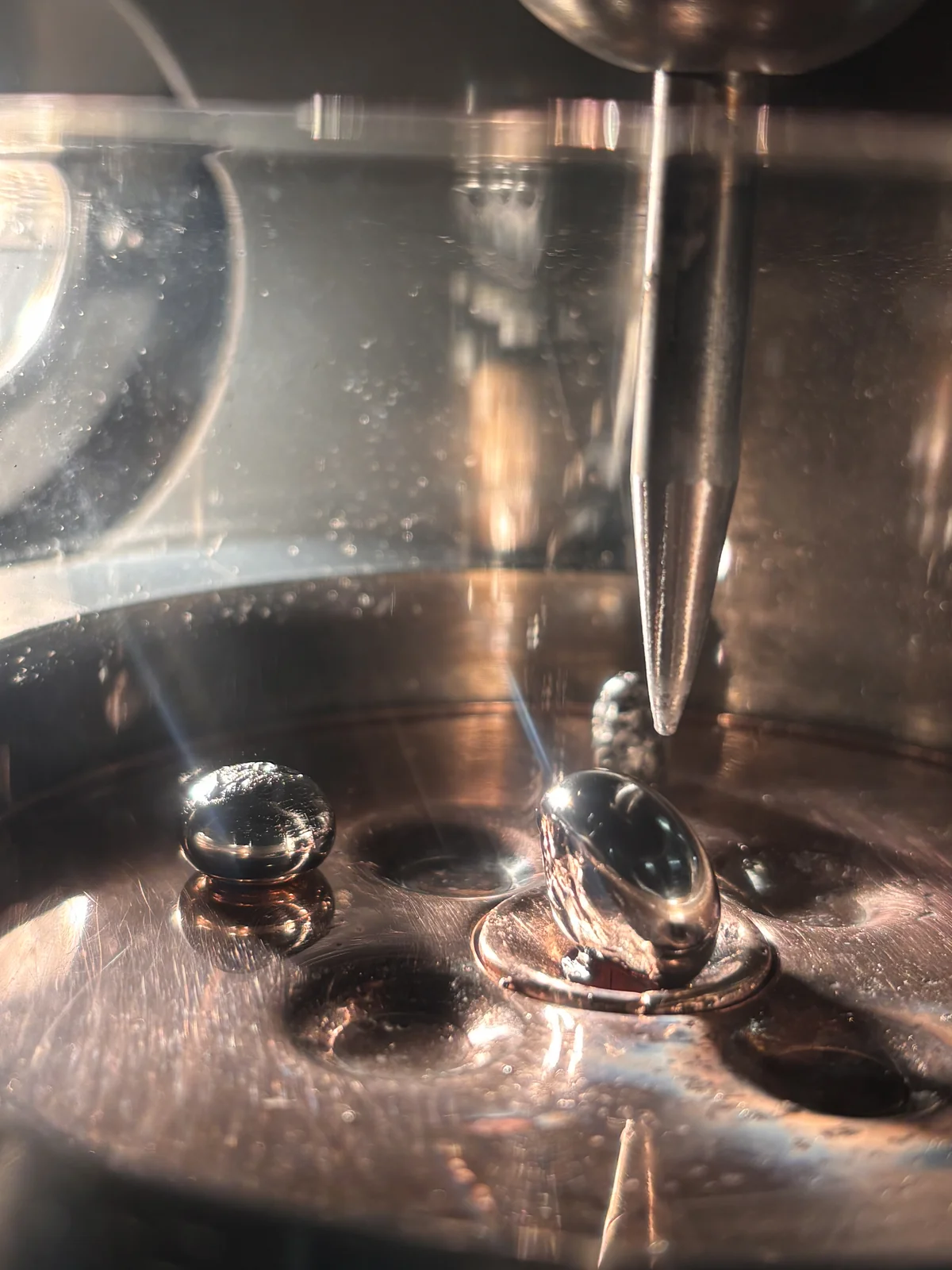 Cast carbon-bronze buttons on the copper hearth of the mini arc melter