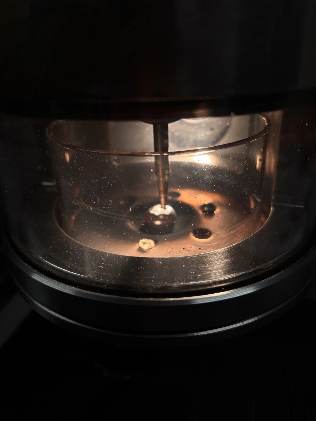 A button of alloy melting beneath the electrode inside the mini arc melter