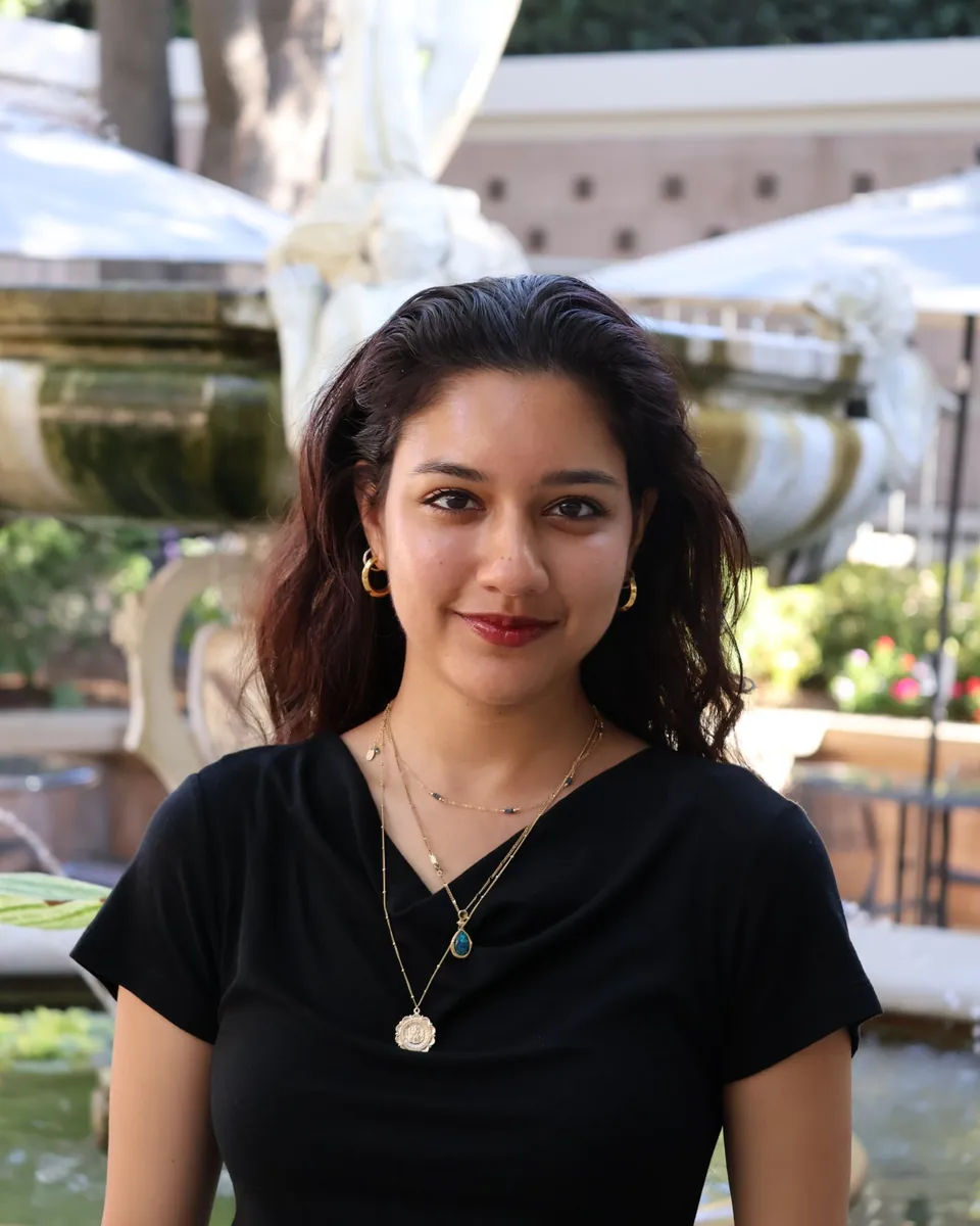 Samara Baidwan, smiling, outdoors in front of a fountain