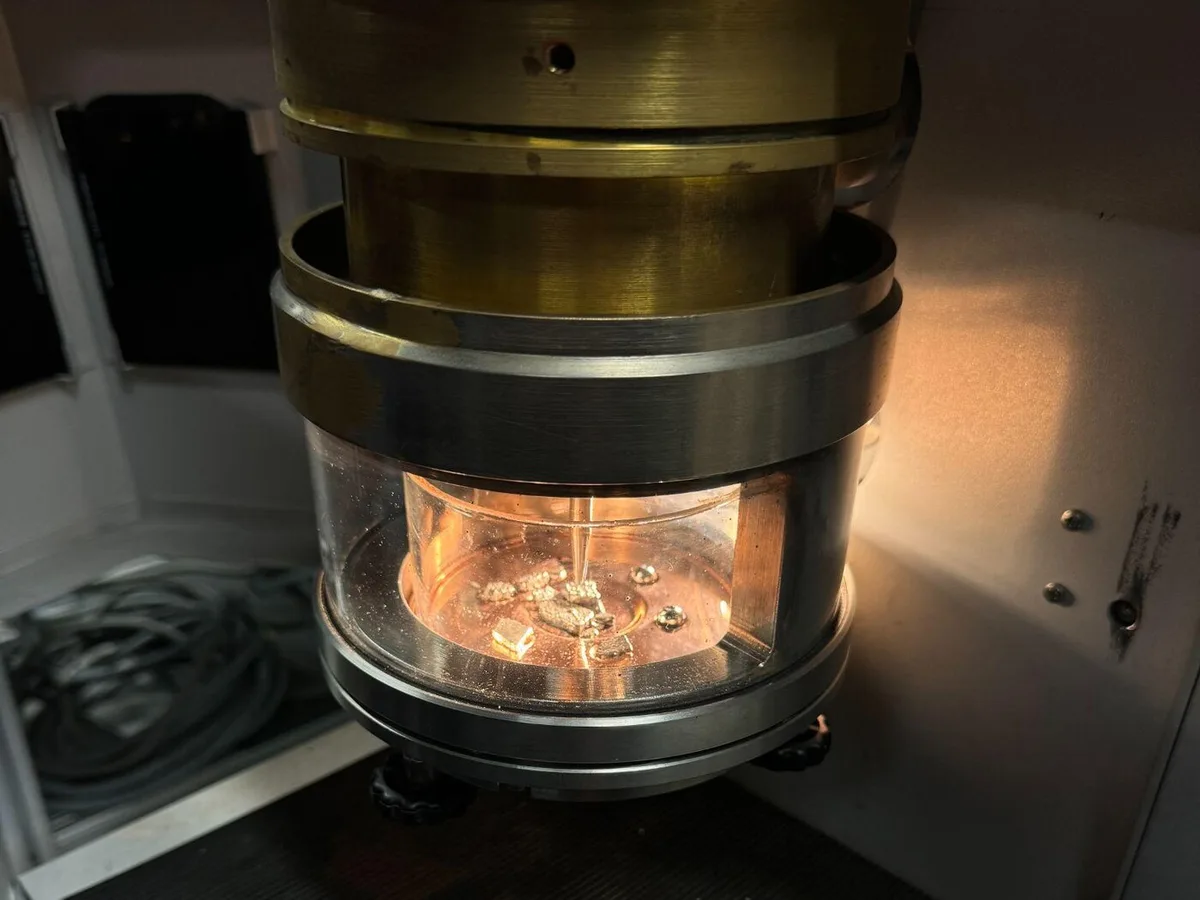 Molten carbon-bronze alloy glowing inside the chamber of a mini arc melter
